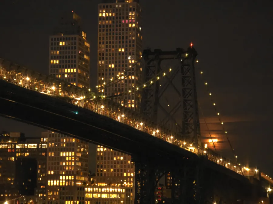A steel bridge crossing in front of illuminated apartment buildings