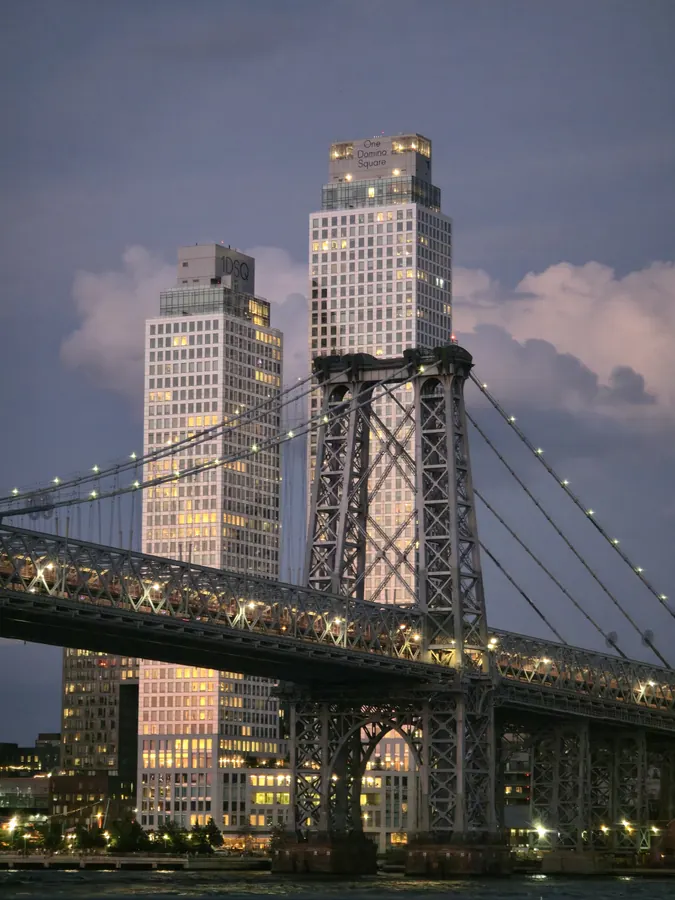 A bridge tower framed by city buildings in the evening