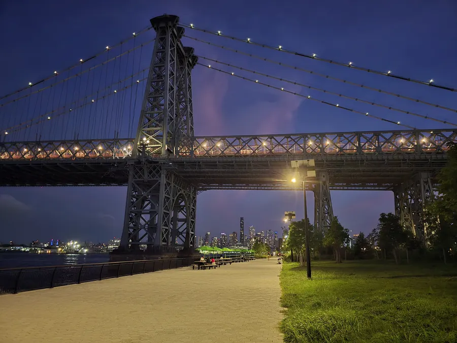 A suspension bridge lit against a deep blue night sky